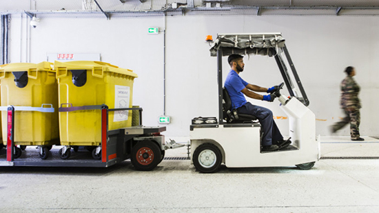 Un employé de Sodexo conduit un petit camion pour déplacer des poubelles