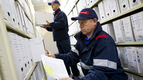 Two Sodexo employees sorting archived boxes of documents