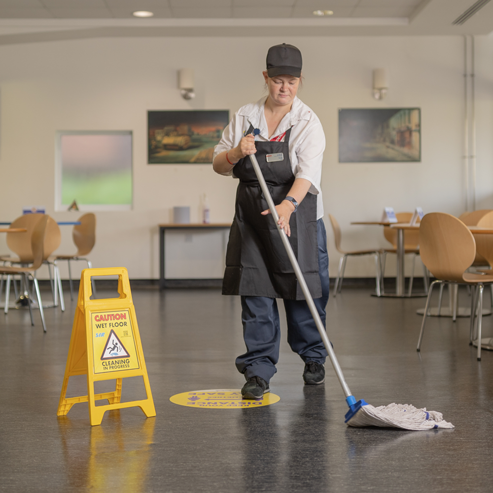 A Sodexo employee mopping the floor of a lunchroom