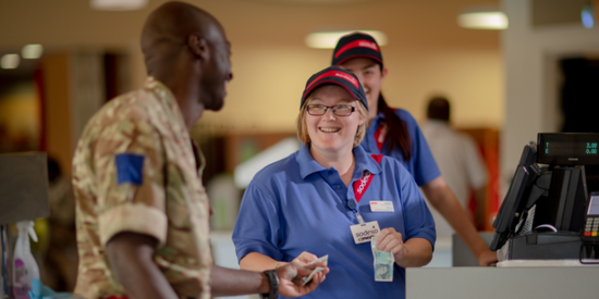two women in Sodexo uniforms smiling at a military man
