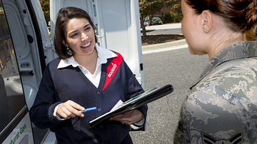 A sodexo employee speaking to an armed forces employee holding a clipboard