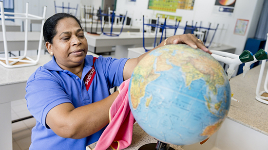 A sodexo employee cleaning a globe in a school classroom