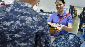 A sodexo employee handing clean uniforms to a member of the armed forces