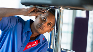 A Sodexo employee repairing kitchen equipment